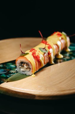 Havyar, somon, yılan balığı, krem peynir, ahşap bir tahtanın üzerindeki peynir soslu suşi.