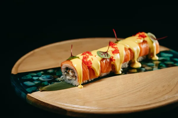 Stock image Sushi Cheese Roll with caviar and salmon, eel, cream cheese, cheese sauce on a wooden board, decorated with microgreens