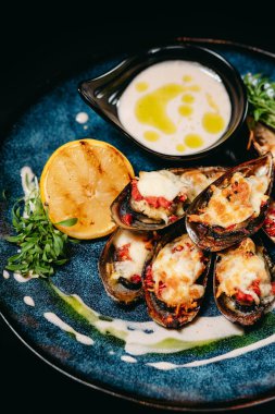 Balık yemeği Yeni Zelanda midyesi. Mavi tabakta fındık-susam sosu ile servis ediliyor.