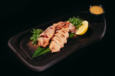 Siyah arka planda limonlu ve sosisli doldurulmuş et.