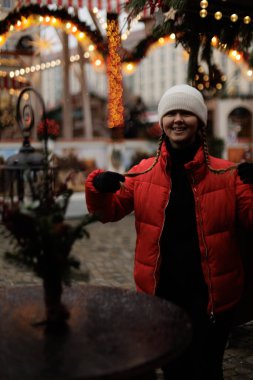 Kırmızı ceketli ve şapkalı genç bir kadın eski kasabadaki bir Noel pazarında