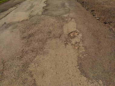 Çatlak ve yıpranmış asfalt bir yol yüzeyinin yakın plan çekimi..