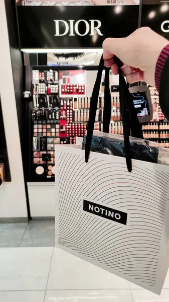 Kozmetik mağazasının yanında bir alışveriş çantası bulunduruyor..