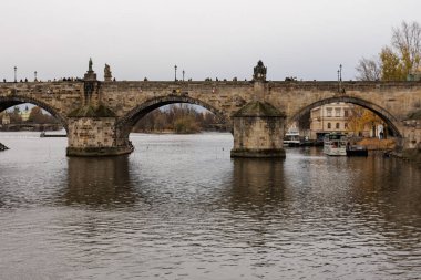 Prag, Çek Cumhuriyeti - 24 Kasım 2023: Tarihi köprü gün batımında sakin bir nehri kapsıyor.