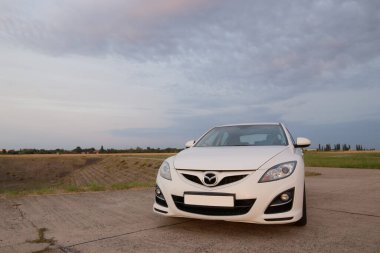 Prag, Çek Cumhuriyeti - 20 Temmuz 2021: Beyaz Mazda 6 gh sedan arabası arka planda bulutlu bir gökyüzü olan bir yol üzerinde park halinde