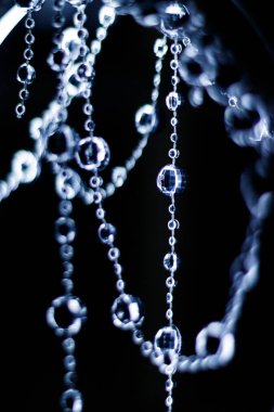 Kristal boncuklar Noel ya da yeni yıl kutlaması için karanlık bir arka planda asılı ve parlıyor.