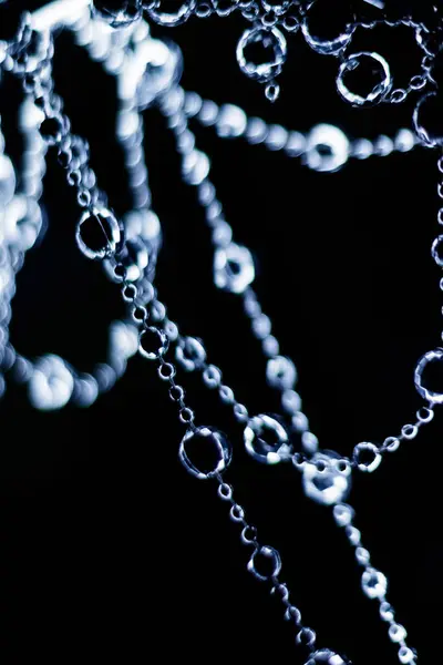 Kristal boncuklar Noel ya da yeni yıl kutlaması için karanlık bir arka planda asılı ve parlıyor.