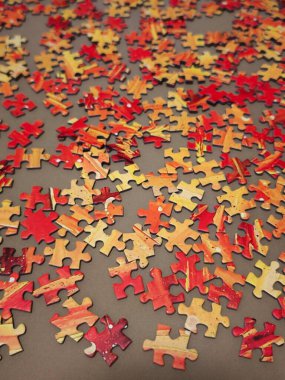 Sıcak turuncu ve kırmızı tonlarda yapboz parçaları bir yüzeye dağılmış, Noel beklentisini uyandırıyor.