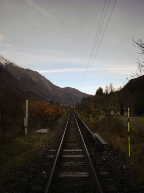 Kızıl tren Chamonix Vadisi 'ndeki bir demiryoluna yaklaşıyor. Fransız Alpleri, karlı dağları ve sonbahar yapraklarıyla.