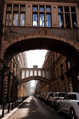 Prague, Czech republic - February 16, 2023: Sunlight streams through a connecting bridge over na prikope street, highlighting the historical architecture and parked cars clipart