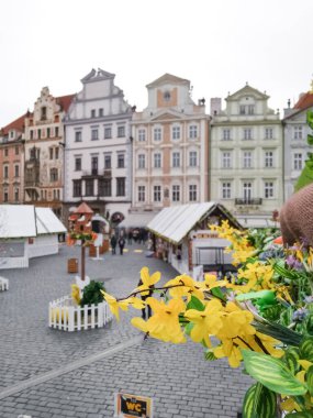 Prague, Czech republic - March 22, 2018: Yellow flowers decorating an easter market in old town square, with colorful buildings in the background clipart