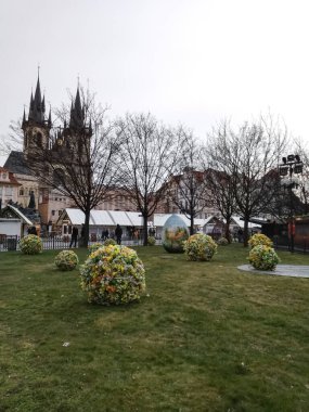 Prague, Czech republic - March 22, 2018: Giant easter eggs and flower spheres decorating old town square with the church of our lady before tyn in the background clipart