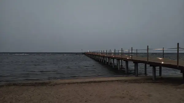 Gün batımında Kızıl Deniz 'e doğru uzanan sakin bir iskele manzarası huzurlu ve rahatlatıcı bir atmosfer yaratıyor.