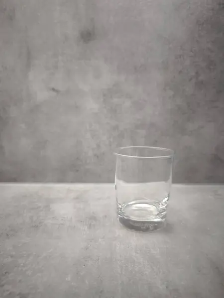 Prag, Çek Cumhuriyeti - 1 Ocak 2025: Gri beton yüzeyde dinlenen berrak Ikea bardağı, geometrik formları ve kentsel dokuları vurgulayan minimalist kompozisyon Dünya Su Günü kopyalama alanı