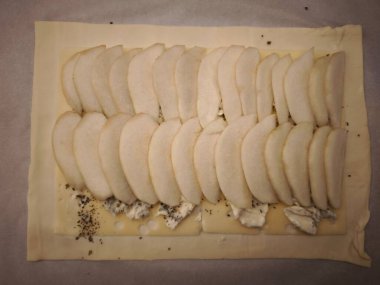 Dilimlenmiş armutlar fırında pişirmeye hazır peynirli ve tohumlu puf börekler. Tatlı ve lezzetli bir karışım. Sevgililer Günü için kolay bir akşam yemeği için mükemmel.