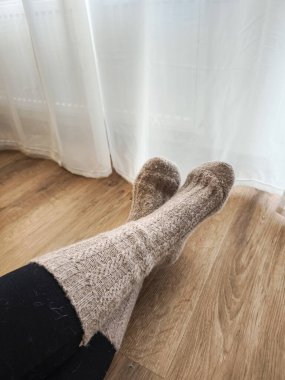 Sıcak örülmüş çoraplar giyen kadın Prag 'da ısıtmanın yanında dinleniyor ve evinde rahat bir günün tadını çıkarıyor.