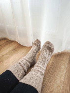 Yumuşak, örülmüş çoraplar giyen bir kadın Prag 'daki ısıtmanın yanında dinleniyor. Sıcaklık ve sükunet dolu bir günün tadını çıkarıyor.