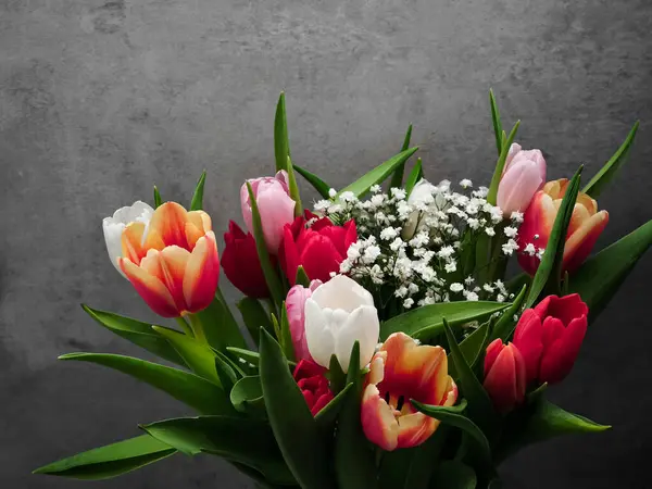 Renkli lalelerden oluşan canlı bir buket ve narin bebek nefesi Anneler Günü için neşeli ve romantik bir atmosfer yaratıyor. Sevgililer Günü için uzay kopyaları.