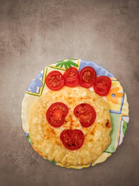 Şaşırtıcı bir yüz tasarımı ile hazırlanmış kiraz domatesli mini süzme peynirli pizzalar renkli bir tabakta servis edilir, sevgililer günü kahvaltısı için mükemmeldir.