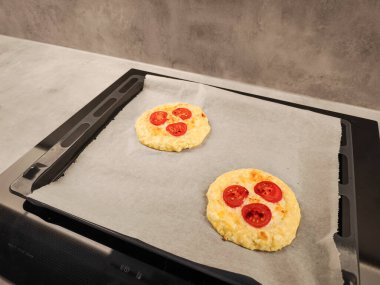 Üzerinde vişneli domates ve erimiş peynir olan mini pizzalar, Prag mutfağındaki fırın tepsisinde romantik bir sevgililer günü kahvaltısı için hazır.
