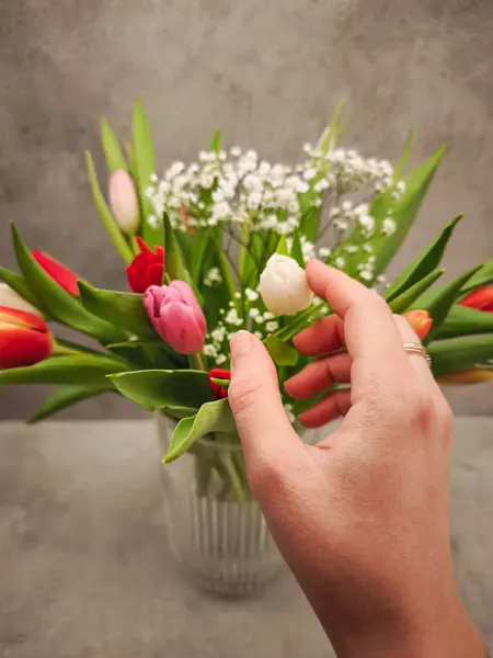 Sevgililer günü için bir buket renkli lale ve bebek nefesi düzenleyen kadın, sevgi ve şefkat sembolü.