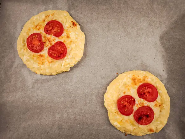 Domatesli ve erimiş peynirli mini pizzalar. Romantik sevgililer günü kahvaltısı için parşömen kağıdının üzerinde dinleniyorlar.