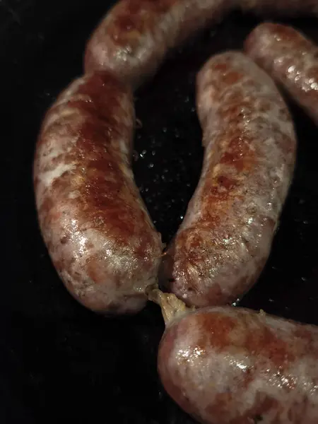 Sosisler cızırdıyor altın kahverengiler, Chamonix, Fransa 'da kıtır kıtır dağ sonbaharı boyunca siyah tavada ısıtılıyor.