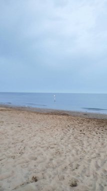 Temmuz ayındaki bibiyolon plajı manzarası, sakin sular ve engin bir gökyüzü. Kumlu sahil, sakin bir akşam gökyüzünün altında yumuşak dalgalarla karşılaşıyor.