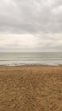 Bibione sahilinin kumlu kıyılarını silip süpüren yumuşak dalgalar, veneto, italyan, yumuşak bulutlu ufuklar kıyı manzarasını kucaklıyor.