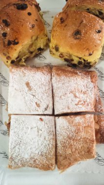 Taze pişmiş hamur işleri, bazıları çikolata parçacıklarıyla dolu ve diğerleri şekerle kaplanmış, davetli bir şekilde bir kağıda oturmuş, eğlenmeye hazır.