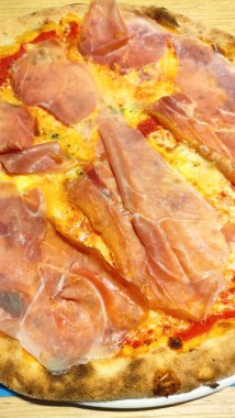 Domates soslu yuvarlak pizza, erimiş peynir ve bir yaz akşamı bibiyo, İtalya 'da servis edilen prosciutto cotto dilimleri.