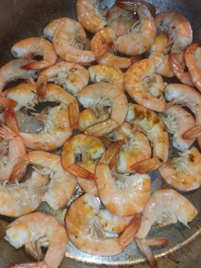 Dökme demir tavada cızırdayan karidesler, bibione 'daki kıyı mutfağında akan güneş ışığı, taze Akdeniz mutfağı geleneğini ön plana çıkarıyor.