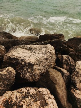 Coastal rocks in bibione, italy, meet the sea, showcasing the natural beauty of veneto's shoreline with waves crashing against rugged stones clipart