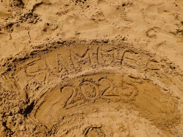 Kum plajı yüzeyi 2025 yazını gösteriyor. Yazın yazlık, sahil şeridinde beklenen tatil beklentilerini yakalıyor. Arka planlar, grafik tasarım ve iç dekorasyon için mükemmel.