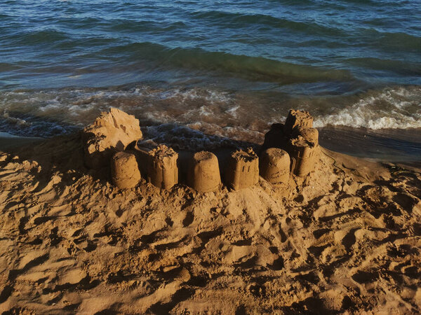 Intricate sandcastle built on the sandy beach of bibione, italy, resisting the gentle waves of the adriatic sea