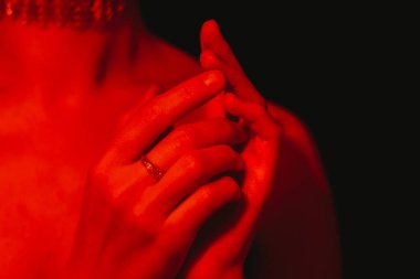 Sıcak bir kırmızı ışığın altında ellerinizi yavaşça kapatın, romantizm ve samimiyet taşıyarak, Sevgililer Günü teması veya kitap kapağı için mükemmel