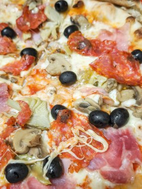 Çıtır kıtır, erimiş peynir, zeytin, mantar ve geleneksel İtalyan lezzetlerini temsil eden tuzlu et içeren taze pişmiş pizza.