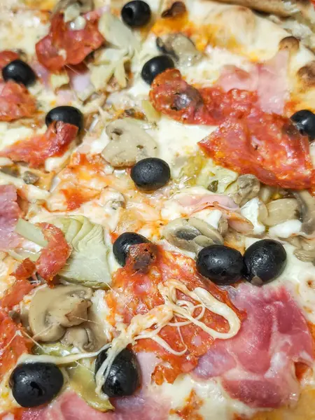 Çıtır kıtır, erimiş peynir, zeytin, mantar ve geleneksel İtalyan lezzetlerini temsil eden tuzlu et içeren taze pişmiş pizza.