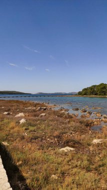 Berrak mavi gökyüzünün altında ahşap bir iskelesi olan sakin Hırvat körfezi yaz boyunca Adriyatik sahillerinin huzurlu güzelliğini gözler önüne seriyor.
