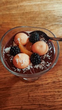 Çikolatalı puding, içinde bisküviler, böğürtlenler, şekerli portakal lezzeti ve ahşap masa strbske pleso üzerinde parçalanmış hindistan cevizi, yüksek tatralar olan bir bardakta servis edilir.