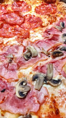 Jambon, mantar ve baharatlı salamın yer aldığı taze pişmiş bir pizzanın kapanışı Prag, Czechia 'daki lezzetli lezzet kombinasyonlarını gözler önüne seriyor.