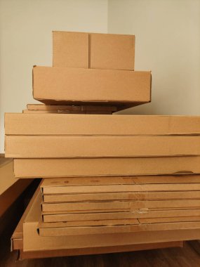 Karton kutular düzgünce bir odanın köşesine istiflenmiş, depolamayı, organizasyonu ve taşınmayı veya taşınmayı sembolize ediyor.