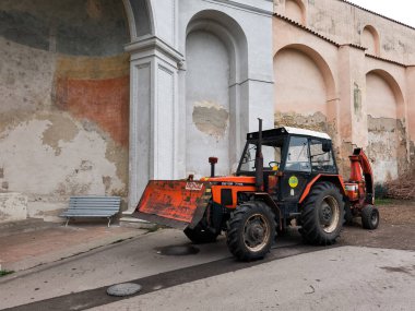 Prag, Çek Cumhuriyeti - 26 Mart 2025: Prag caddesinde yıpranmış bir duvarın önünde park etmiş kırmızı zetor traktörü, kırsal yaşamı kentsel manzara vojan bahçelerine harmanlıyor.