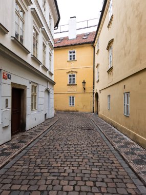 Prag, Çek Cumhuriyeti - 26 Mart 2025: Tarihi Prag, Czechia kentinde kırmızı kiremit çatılı sarı bir binaya çıkan dar kaldırım taşı sokağı