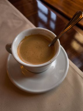 Lungo, Prag, Czechia 'da bir kafede çay kaşığıyla çay tabağının üstüne oturur. Hoş bir bahar günüdür.