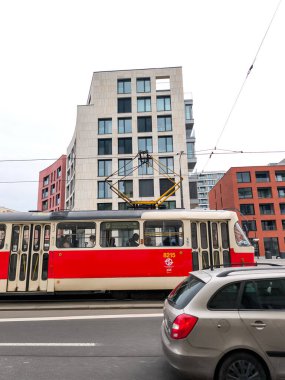 Prag, Çek Cumhuriyeti - 24 Mart 2025: Zizkov ilçesinden yolcu taşıyan kırmızı ve bej tramvay, modern ve geleneksel mimarinin harmanı olan Prag 3 jana zelivskeho caddesinden geçiyor