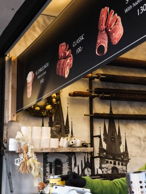 Prag, Çek Cumhuriyeti - 10 Nisan 2025: Prag, Czech cumhuriyetindeki Tyn Kilisesi 'nin resmiyle süslenmiş bir Noel pazarında trdlo hamur işi satan sokak satıcısı