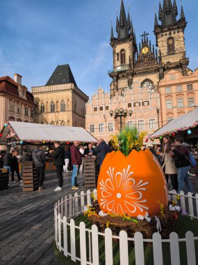Prag, Çek Cumhuriyeti - 10 Nisan 2025: Prag, Czech cumhuriyetindeki eski kent meydanını aydınlatan dev paskalya yumurtası, ziyaretçiler bayram pazarı ve yakındaki Tyn kilisesinin keyfini çıkarıyor