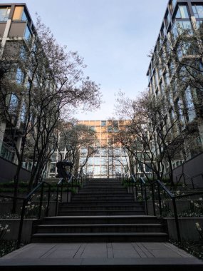 Prag, Çek Cumhuriyeti - 10 Nisan 2025: Prag, Czechia 'da cam cepheli ve ağaçlı modern ofis binaları, günün sonunda bir merdivenden görüldü