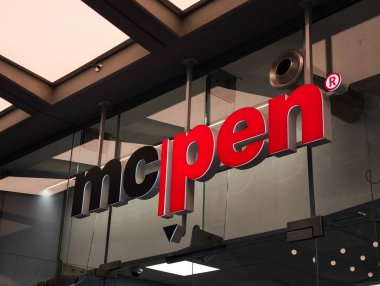 Prag, Çek Cumhuriyeti - 15 Nisan 2025: Bir alışveriş merkezinde asılı kırmızı ve siyah Mcpen logosu, cam panellerden aydınlatılmış ve görünür